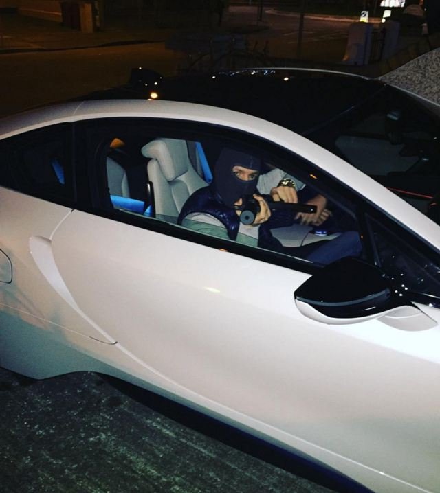 Conor McGregor in a BMW i8 pointing an air-soft gun